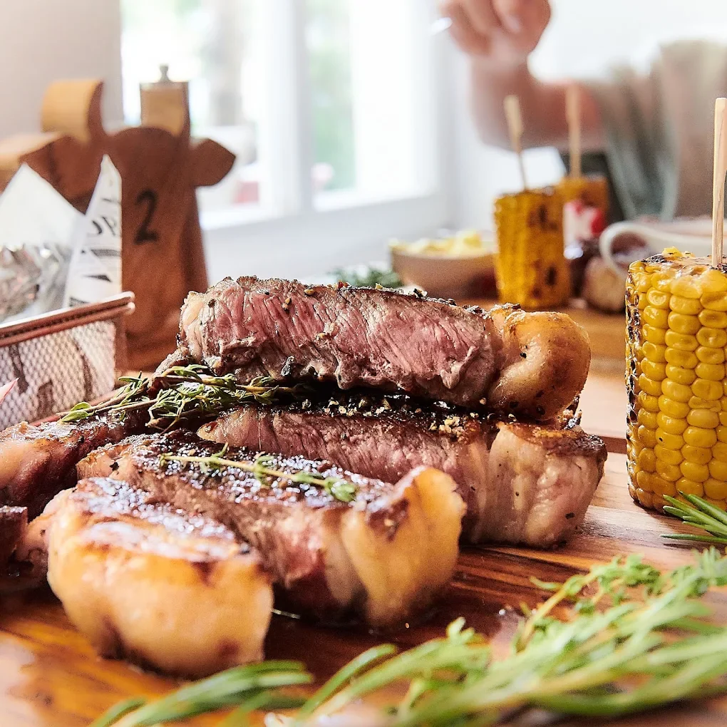Aufgeschnittenes Steak auf dem Holzbrett mit Maiskolben