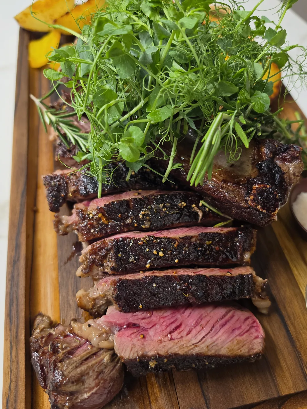 Aufgeschnittenes Steak auf dem Holzbrett mit frischer Kresse